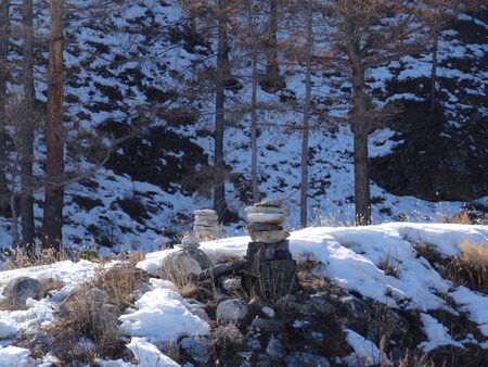 pyramids of flat light gray stones are illuminated by the sun against the dark shadowy slope in winterの写真素材