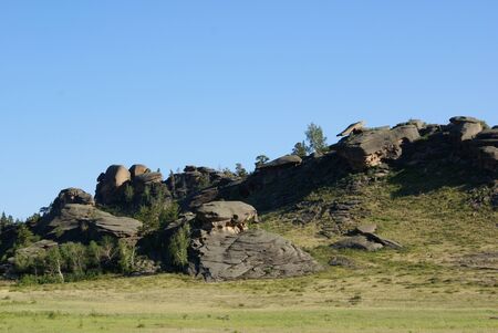view of a mountain range with ledges and rocks of unusual shape against the background of blue sky and green vegetationの写真素材
