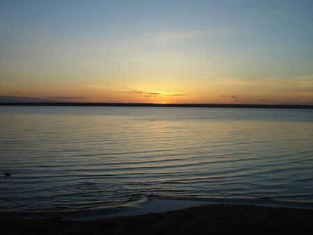 the sun sets on the horizon above the seaの写真素材