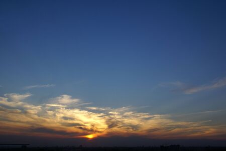 very beautiful bright rich blue with white cloud streaks highlighted by the setting sunの写真素材