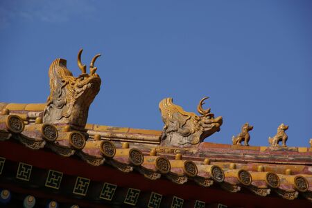 wooden figures of dragons on the roof of the pagoda against the blue sky close upの写真素材
