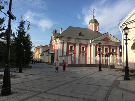 view of the street where people walk next to the Church building with terracotta wallsの写真素材