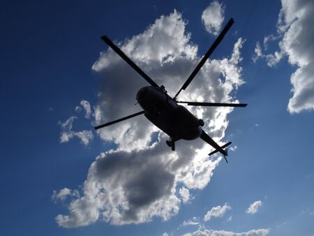 a helicopter is flying in the blue sky with white cloudsの写真素材
