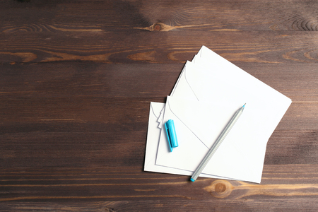 stack of white envelopes on a wooden background. top view, mock up, flat layの写真素材
