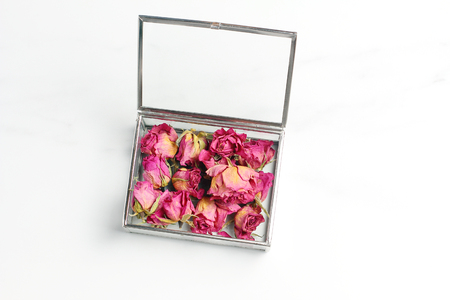 buds of roses in a glass box on a marble table. pink dried flowers. creative layout, minimal concept, flat layの写真素材