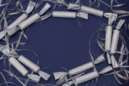 Candy in a silver wrapper and ribbon on a dark blue background. New year decor. Top view, flat lay, copy space.の写真素材