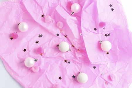Christmas decor. white balls and gold confetti on a pink background. flat lay, top view.
