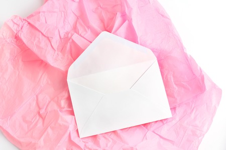 open white envelope on coral background. invitation to a holiday. flat lay, copy space.の写真素材