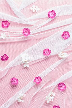 floral pattern. white fabric in form of veils and fresh flowers. flat lay, vertical frame