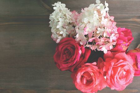 bouquet of red roses and hydrangea fresh flowers in on dark wooden table. retro filter, copy space, flat lay.の写真素材
