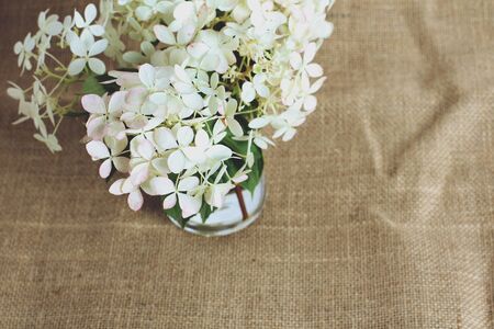 bouquet of white hydrangeas fresh flowers on jute canvas. retro filter, copy space, flat lay.の写真素材