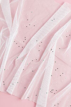 gentle composition of white tulle on a pink background. flat lay, top view wedding concept, vertical...