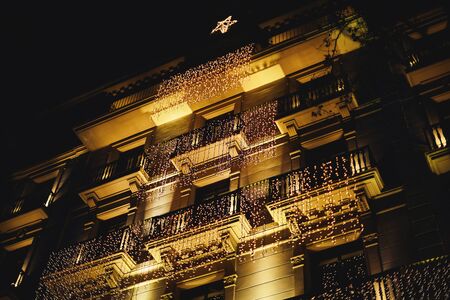 Decorated house with christmas lights. many garlands hung on the balconies of the historic building in Barcelona in the form of a Christmas tree with a star.の写真素材