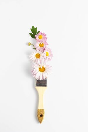 floral creative concept. paintbrush and lilac paint. fresh chrysanthemum flowers on white background. flat lay, vertical frame, copy space.の写真素材