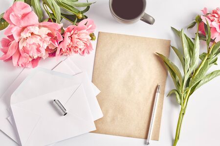 a beautiful bouquet of peonies on office desk. writing supplies and a coffee mug. women workspace, flat lay, space for a text.の写真素材