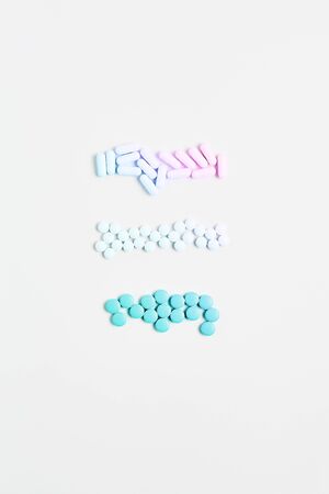 minimal concept. composition of pills and capsules of pastel gradient color on a white background. vitamin skincare, vertical frame, copy space.の写真素材