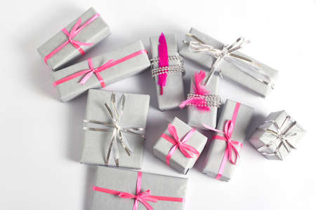 holiday concept. Christmas gifts are wrapped in beautiful gray paper and decorated with silver and pink ribbons and decor on a white backgroundの写真素材