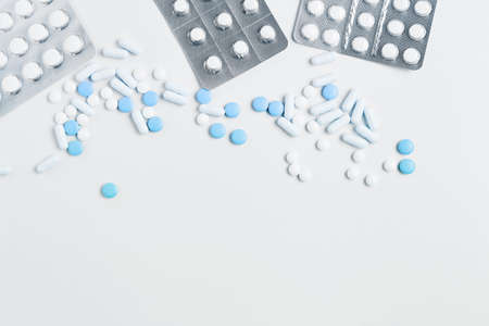 blue pills and capsules in blisters on of white background. composition on a medical theme. flat lay, copy space.の写真素材