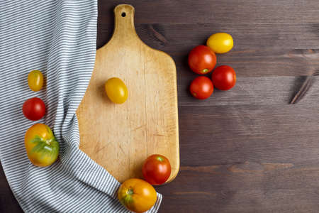 organic vegetables on a wooden cutting Board. ripe tomatoes and a striped kitchen towel. space for text, top view.の写真素材
