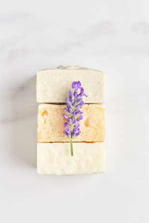 a stack of hand-made soap, decorated with a fresh lavender branch on a marble background. flat lay,...