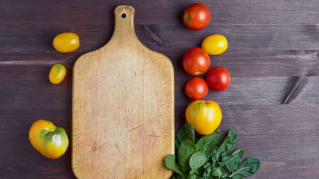 organic vegetables on a wooden cutting board. ripe tomatoes. copy space, flat lay.の写真素材