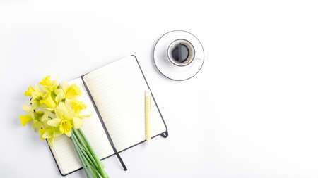 femine workspace long banner. white work desk with coffee mug, notepad, pen and spring flower. simple flat lay, copy space.の写真素材