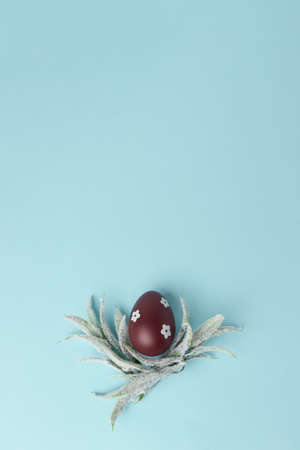 holiday Easter concept. simple composition of a decorative Easter egg and fluffy twigs on a blue background. top view, copy space.の写真素材