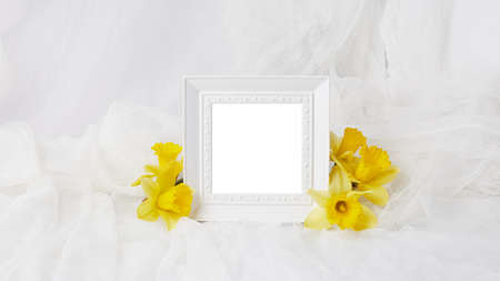 floral banner with place for text. composition of spring flowers and a photo frame in white. layout for invitation, postcard mock-up.の写真素材