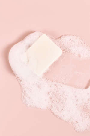 hand made soap in lush white foam on a pink background. cosmetic background minimalistic concept. vertical frame.の写真素材
