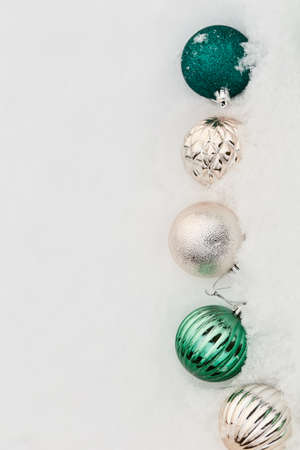 minimalistic composition of New Year's decor on a white background of snow. green and gold glittering balls, simple flat lay.の写真素材