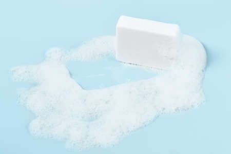 hand made soap in lush white foam on a light blue background. cosmetic background banner.の写真素材