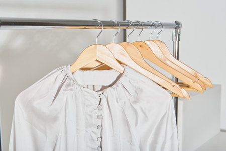 silk beige shirt hanging on a wooden hanger close-up. concept of online trading, light studioの写真素材