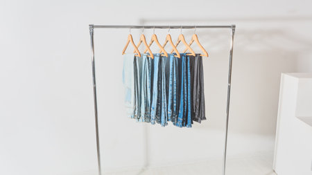 light minimalistic studio with a mobile clothes hanger. clothes rail with jeans of different colors hanging on hangersの写真素材
