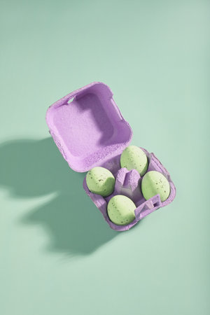 open cardboard box for eggs in purple color on an empty light green background. light green...