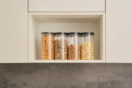 transparent jars for storing various healthy snacks in the kitchen close-up. modern kitchen cabinets...