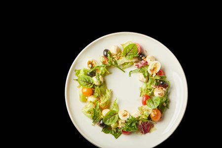 Vibrant salad composed of mixed greens, colorful cherry tomatoes, and nuts arranged beautifully on a white plate.の写真素材