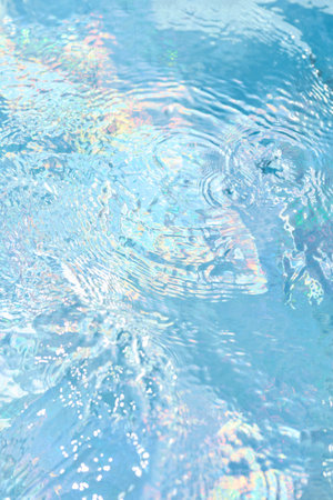 Delicate ripples dance across the surface of a crystal-clear swimming pool. Sunlight casts vibrant...