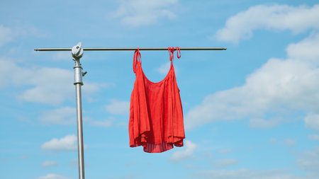 A bright red dress is displayed against a blue sky, perfect for summer fashion mockups. layout for clothing advertisements.の写真素材