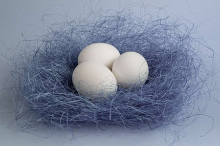 White Easter eggs in a nest on a purple violet background. Minimal concept, close-upの写真素材