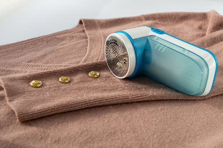 Portable shaver, trimmer, device for removing lint, fluff, pellets from clothes on a cashmere sweater. Clothing care. Slow fashion. Longer use of clothingの写真素材