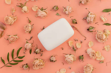 Top view of a bar of soap on a playful pink background with dried rose flowers. The concept of hygiene and skin careの写真素材