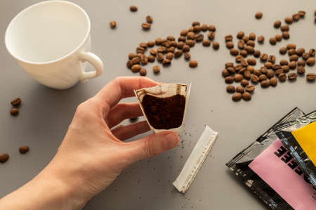 Young woman preparing a modern filter coffee in a drip bag at home. Step 2: Open drip bagの写真素材