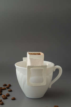 Young woman preparing a modern filter coffee in a drip bag at home. Step 3: Pour hot waterの写真素材