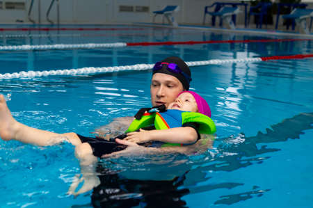 Happy father enjoying teaching his little daughter how to swim in swimming pool. Concept of health and a happy family.の写真素材