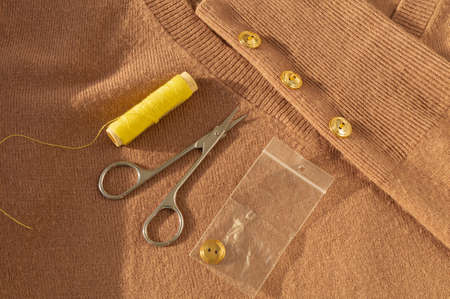 Yellow threads, scissors, buttons, a set of sewing accessories on a cashmere sweaterの写真素材