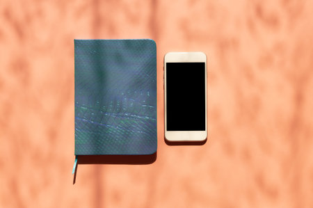 Top view flat lay with notepad and smartphone with copy space on yellow pink background in minimal style, sunlight and shadows. Template for blog social mediaの写真素材