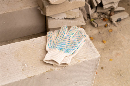 Used working protective gloves lying on grey cement blocks, DIY house building conceptの写真素材