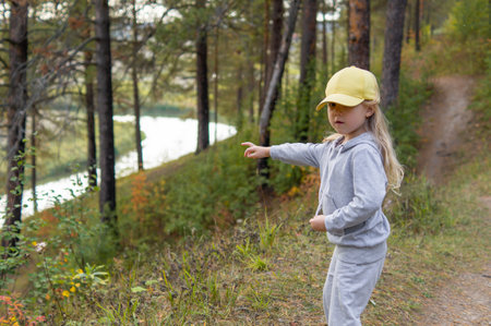 A little cute girl is walking in a beautiful forest in the autumn, she discovered a river and shows it to her mother.の写真素材