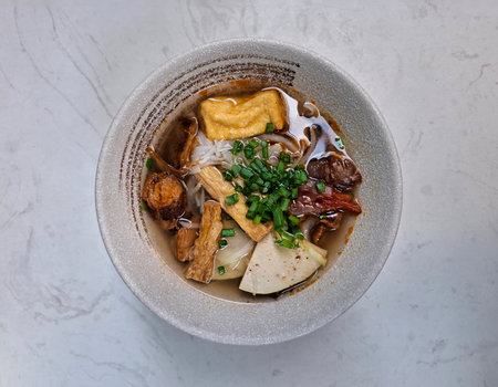 Vietnamese vegetarian pho with tofu, mushrooms, and noodles in a light broth, top view