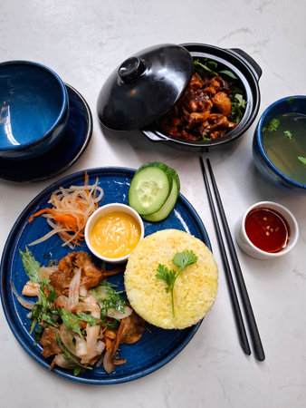 Top view of a Vietnamese vegetarian meal served on a table featuring yellow rice sauteed mushrooms...